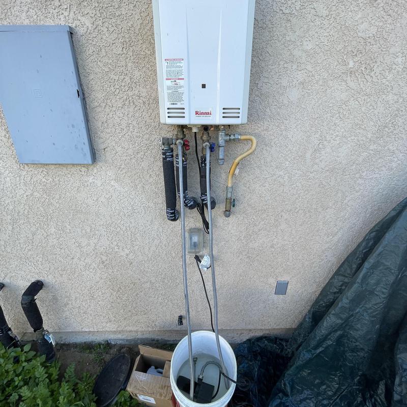 Tankless water heater flushing setup with bucket and hoses