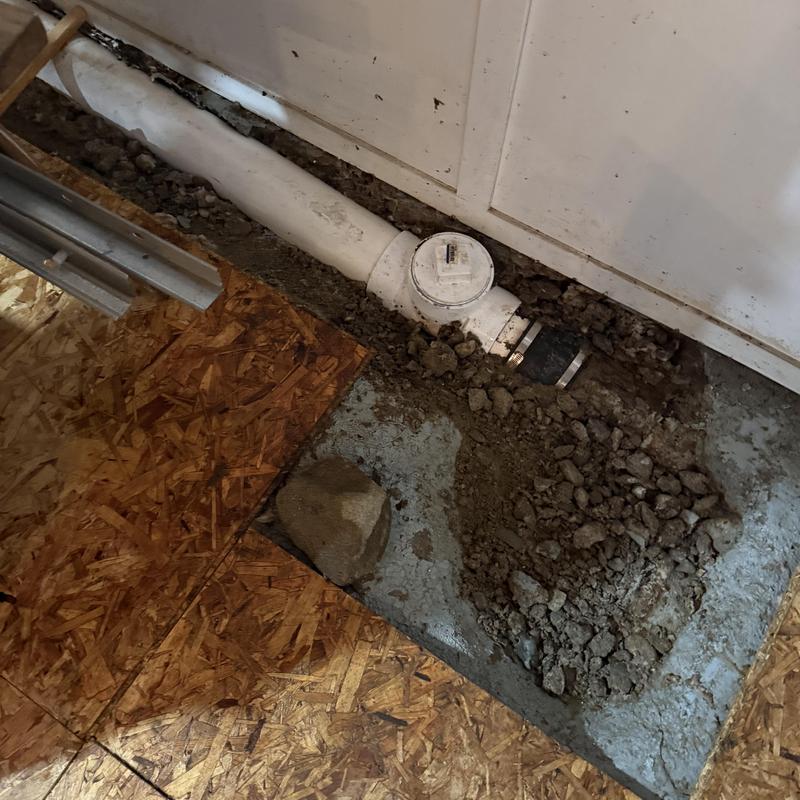 Main sewer line with cleanout cover exposed in floor