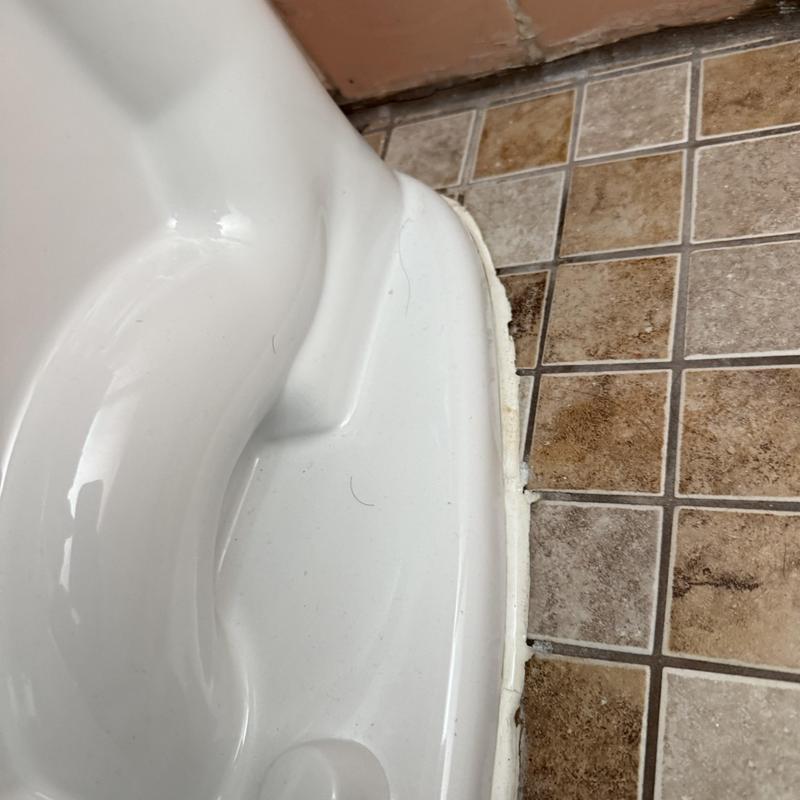 Toilet base with fresh caulking on tiled floor