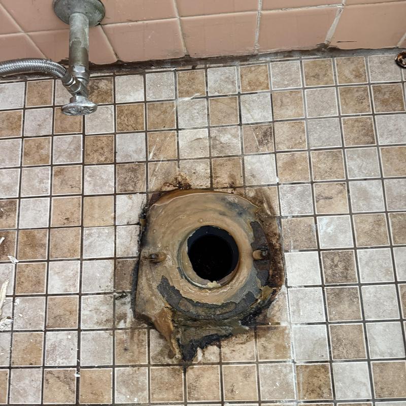 Toilet flange and wax ring replacement site on tiled floor