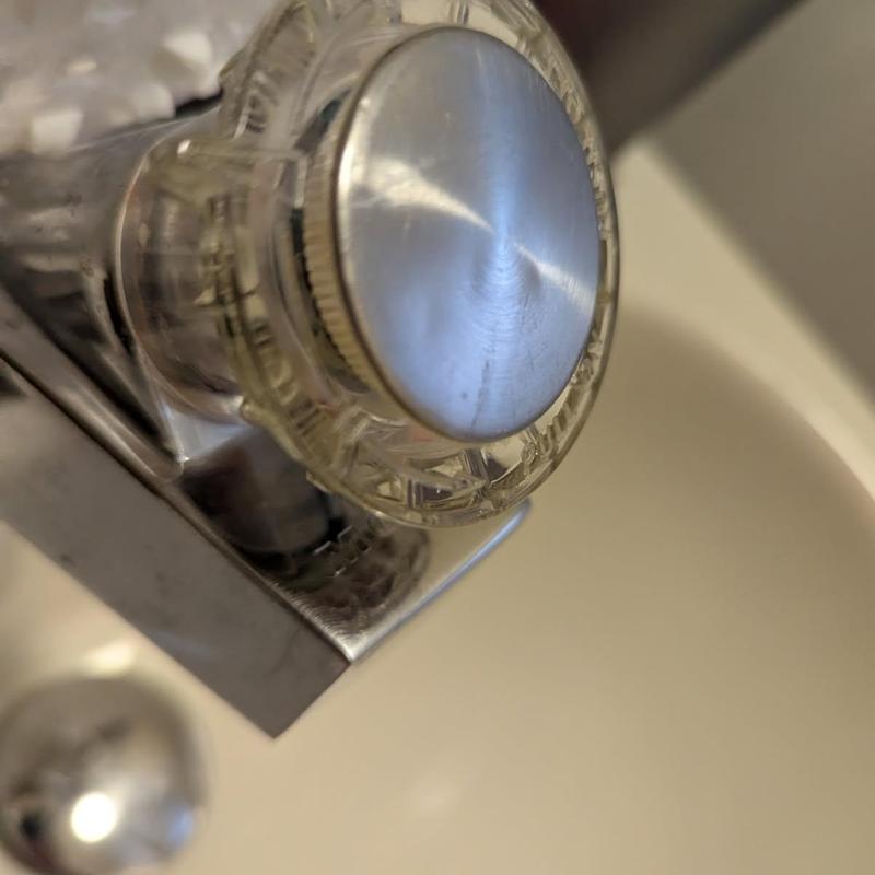 Basin faucet handle and spout close-up in bathroom sink