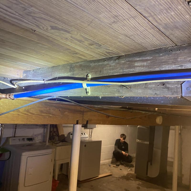 Blue water line piping secured to wooden beam in basement
