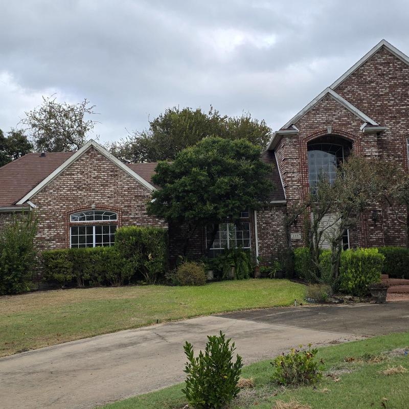 Roof shingles with hail and wind damage on brick house