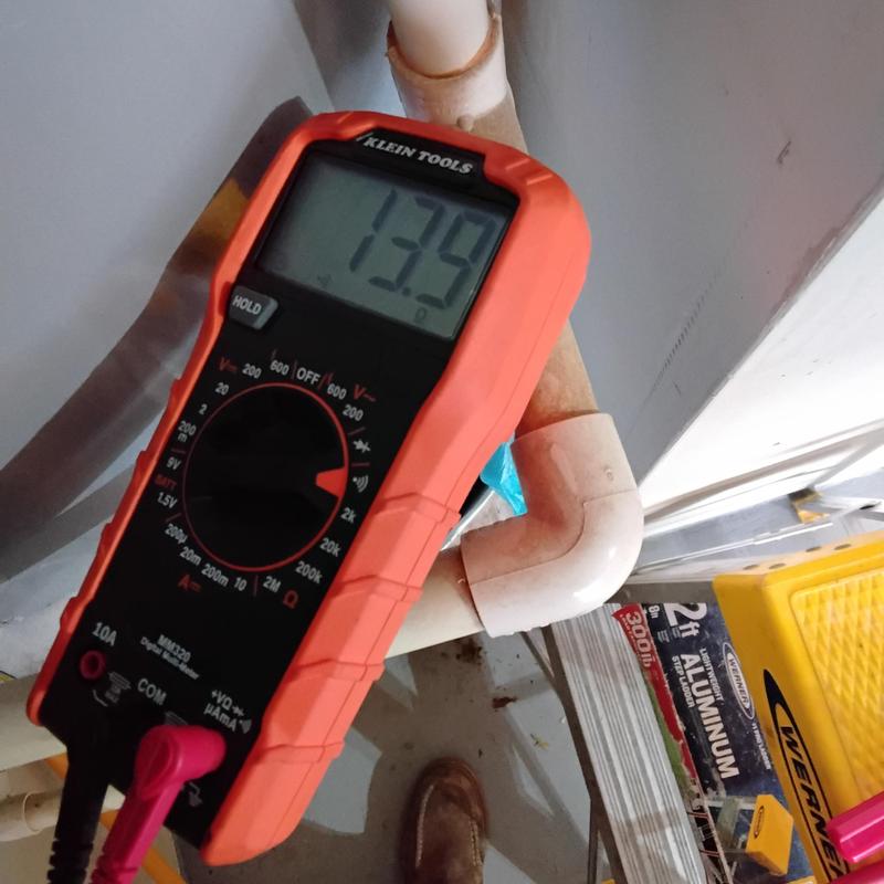 Digital multimeter measuring voltage on plumbing pipe