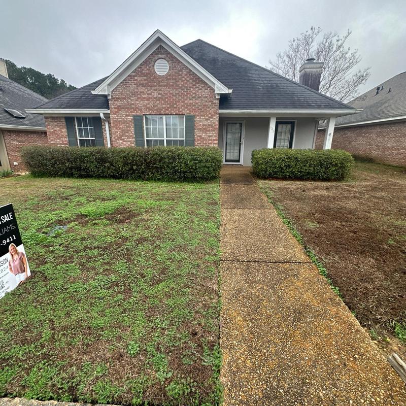 Roof shingles on red brick house under cloudy sky