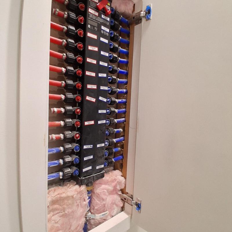 Plumbing manifold with labeled red and blue supply lines Plumbing manifold with labeled red and blue supply lines