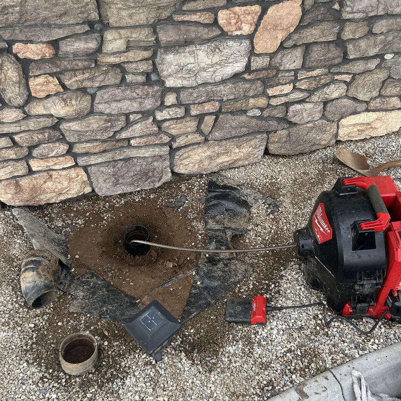 Cast-iron sewer cleanout with sewer snake cable and machine