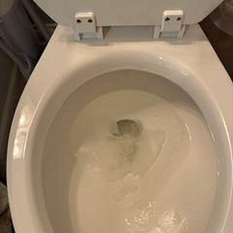 Toilet bowl installation with open seat and flushing water