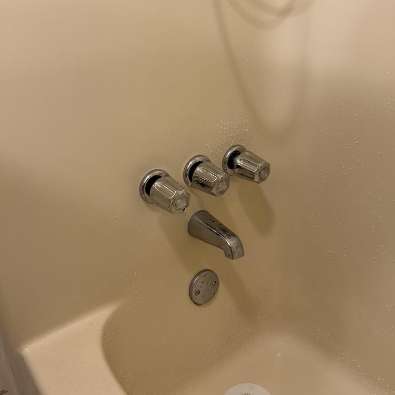 Tub shower faucet with three control knobs in beige tub