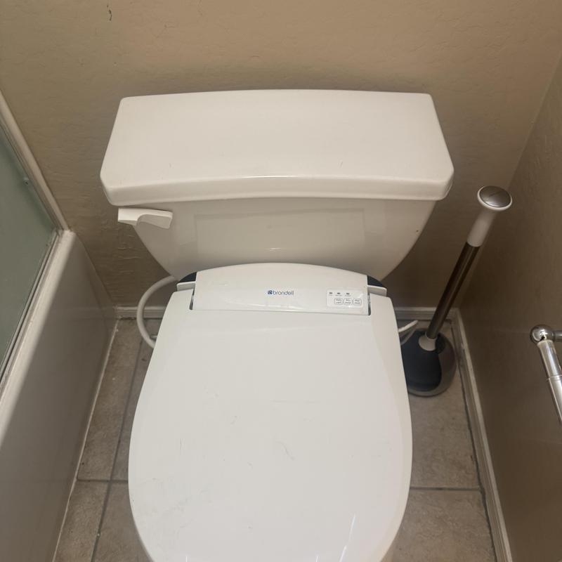 Toilet with bidet seat and plunger near wall