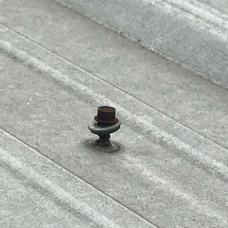 Metal roof fastener with rust on gray panel