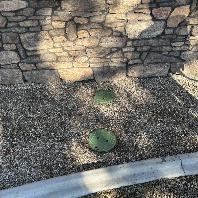 Drain line clean outs with green yard boxes in gravel