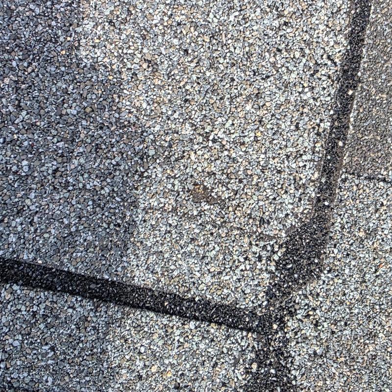 Asphalt roof shingles with hail damage and sealed cracks