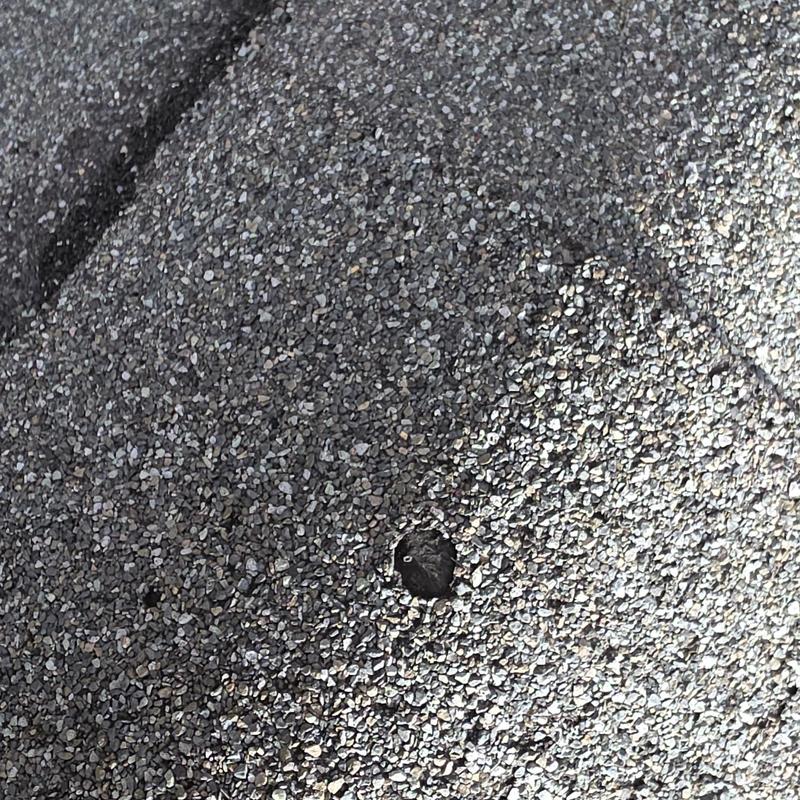 Asphalt shingle with hail impact damage close-up