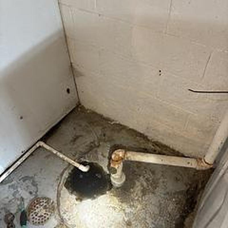 Laundry drain pipes and floor drain in basement corner