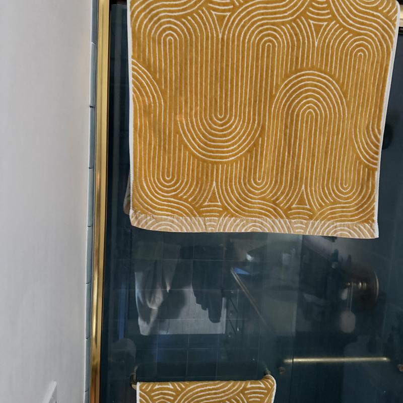 Glass shower door with gold trim and towel rack