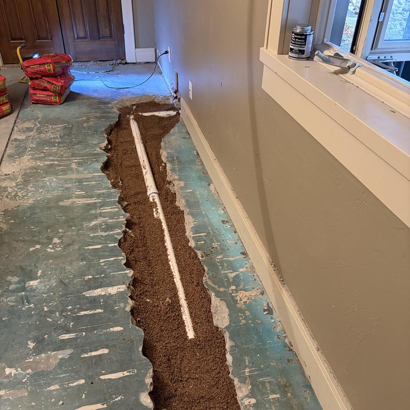 PVC kitchen drain pipe in floor trench with backfill