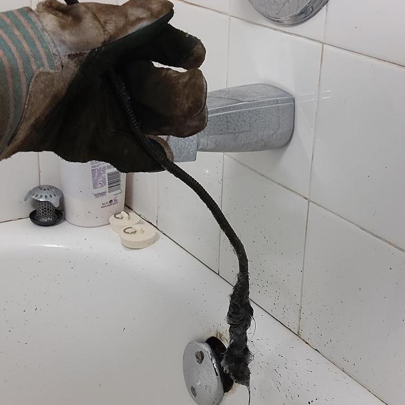 Bath drain clog removal with plumbing snake in tub