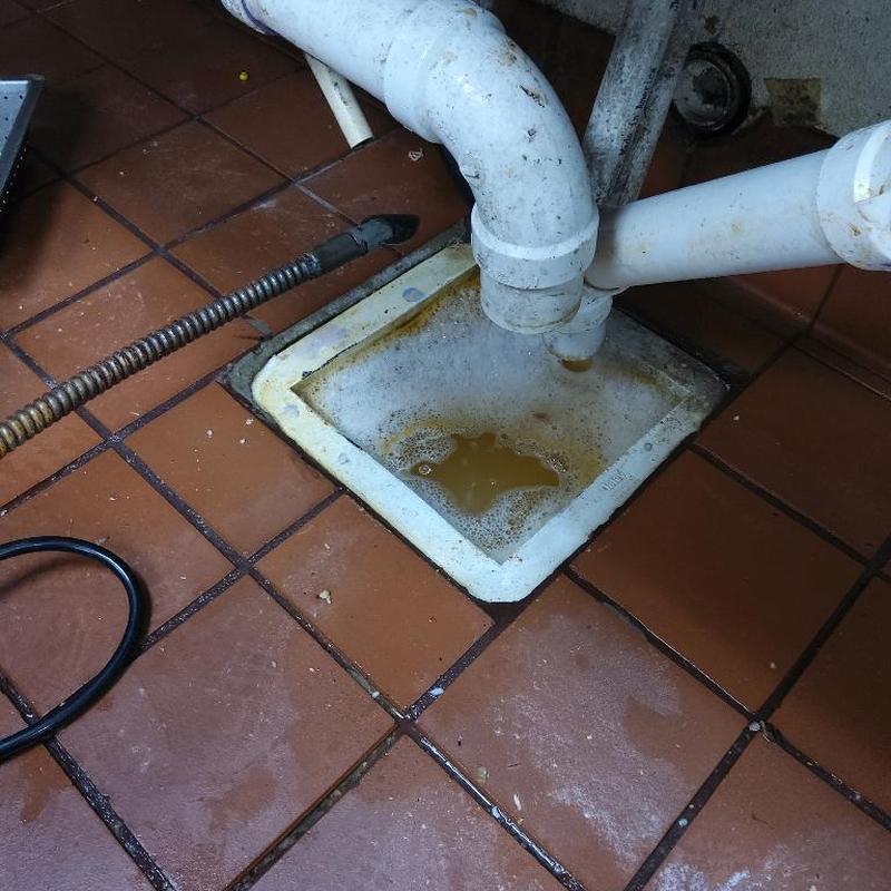 Restaurant floor drain with plumbing pipes and cleaning tool