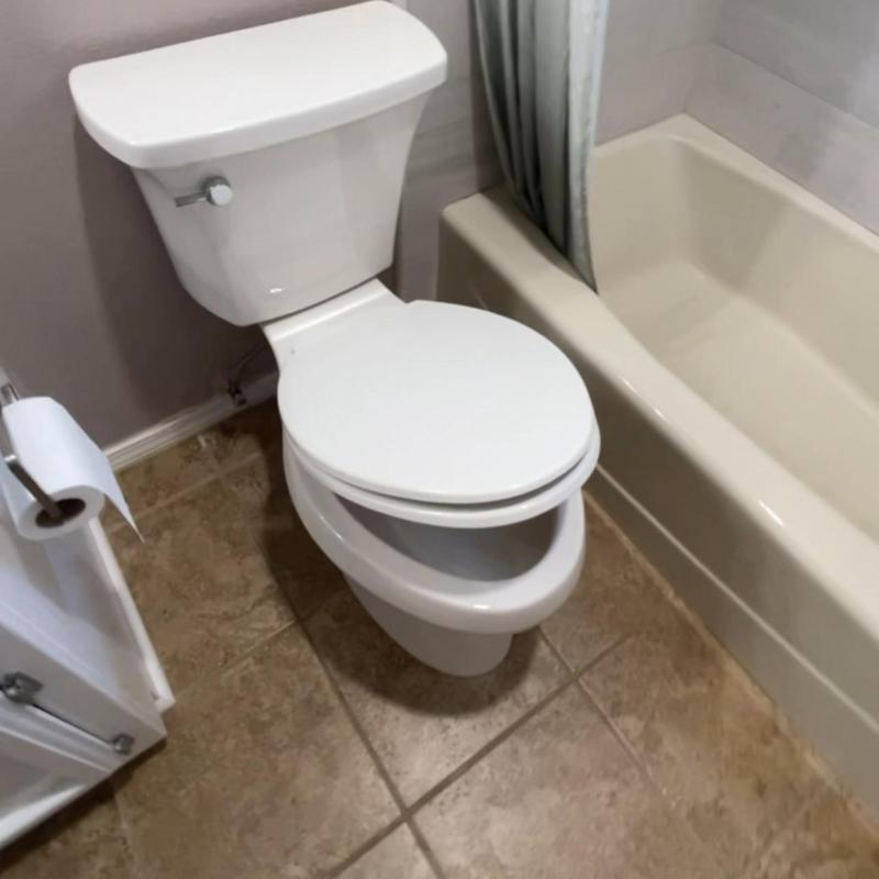 Two-piece white toilet next to bathtub installation