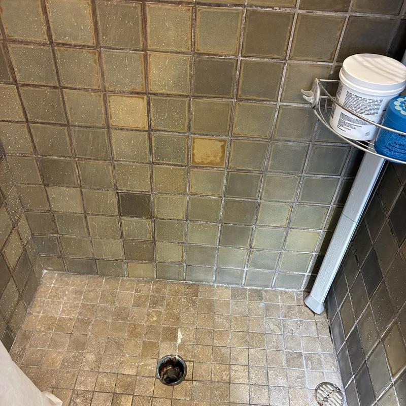 Shower drain with removed clog and tiled walls