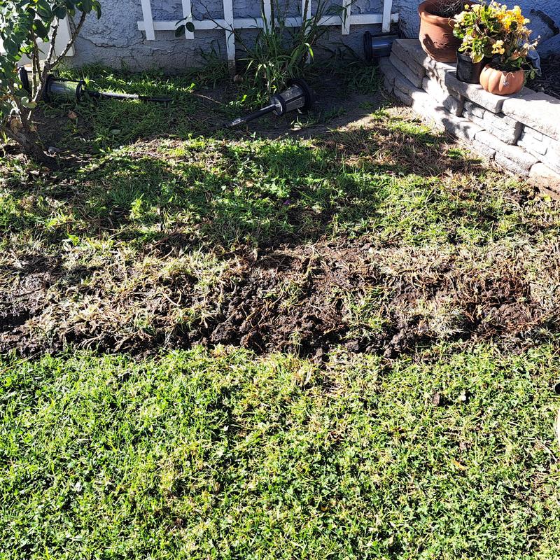 Water main trench in residential yard near flower bed Water main trench in residential yard near flower bed