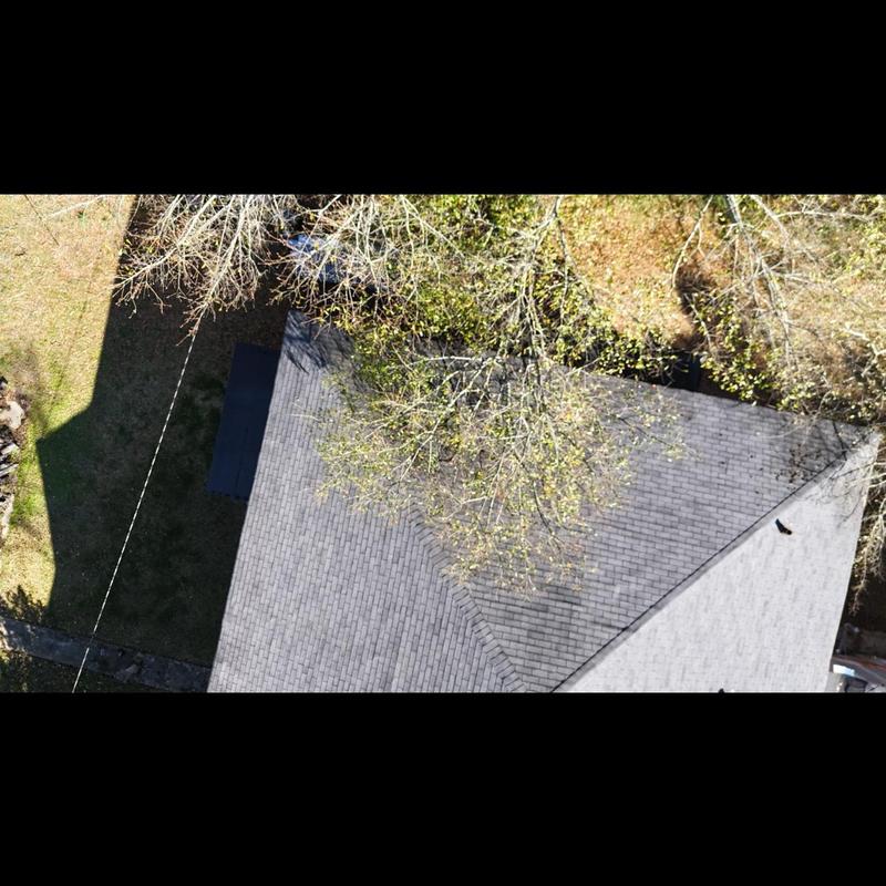 Asphalt shingle roof top with tree shadows and lawn