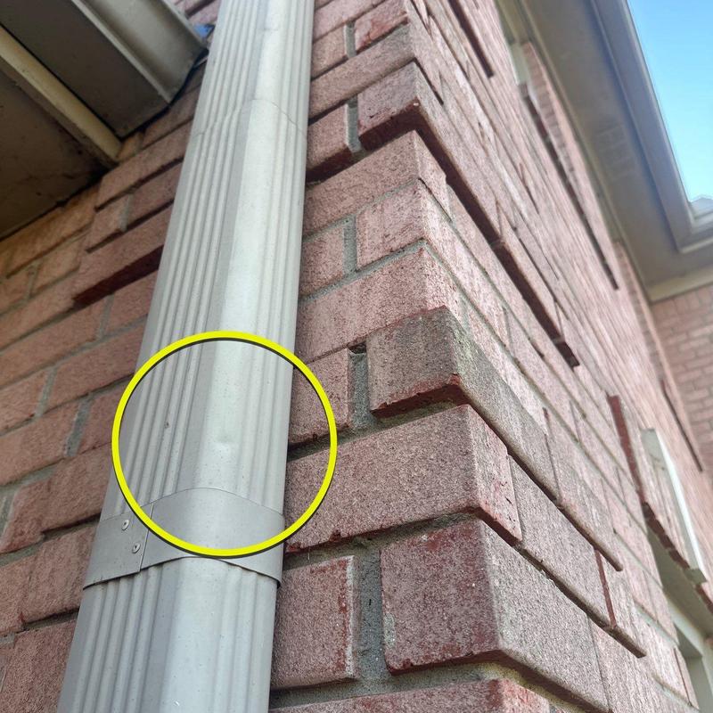 Downspout dent on exterior brick wall