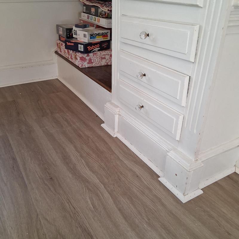 Vinyl flooring installed next to white cabinet baseboards