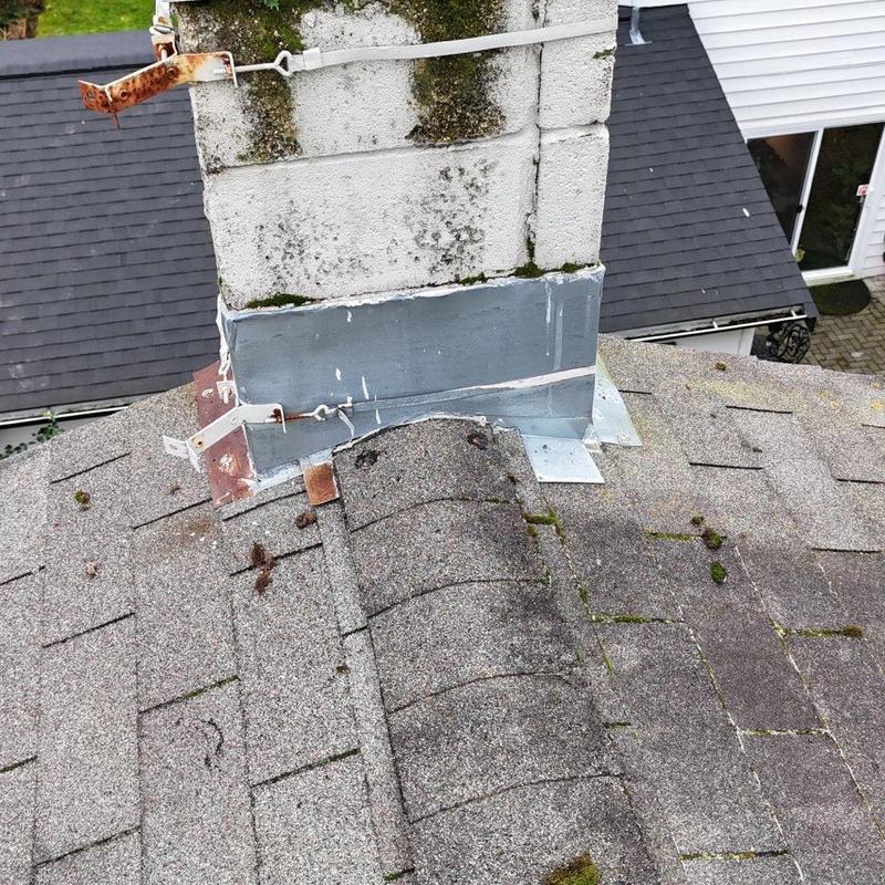 Chimney base and shingle roof inspection with moss buildup