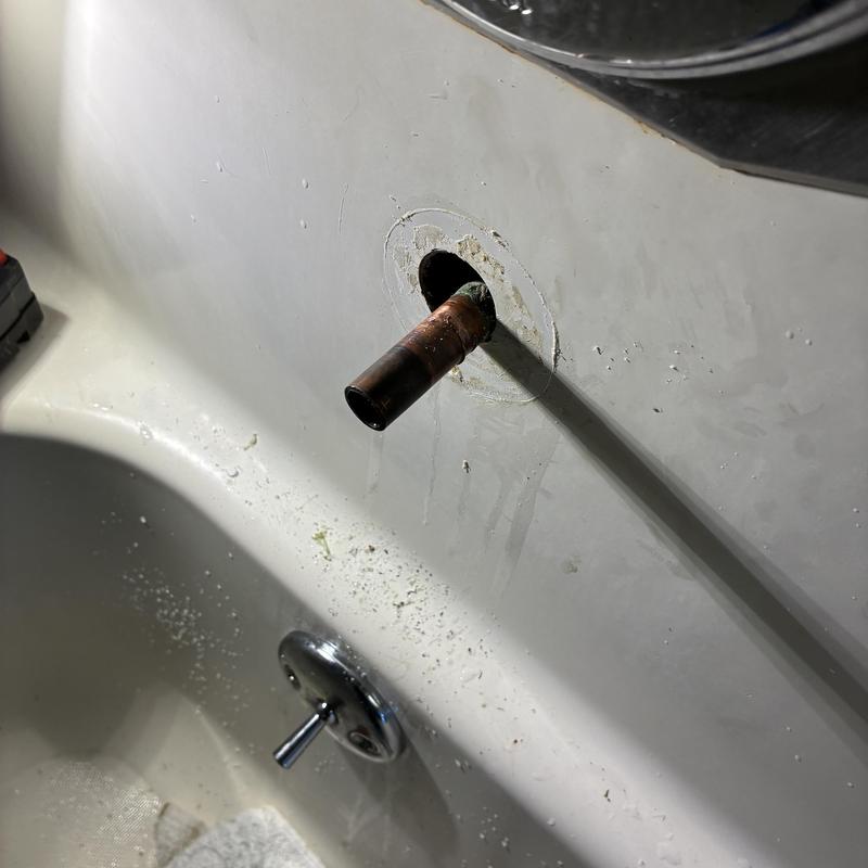 Copper tub spout pipe extending from bathtub wall