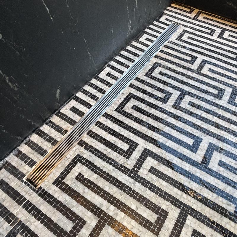 Shower drain grate on patterned tile floor