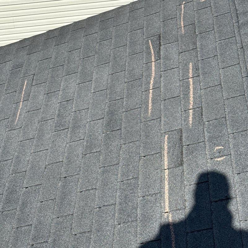 Asphalt shingle roof with hail damage marked for inspection