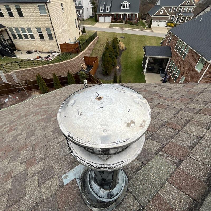 Roof vent on asphalt shingle roof showing weathering and damage