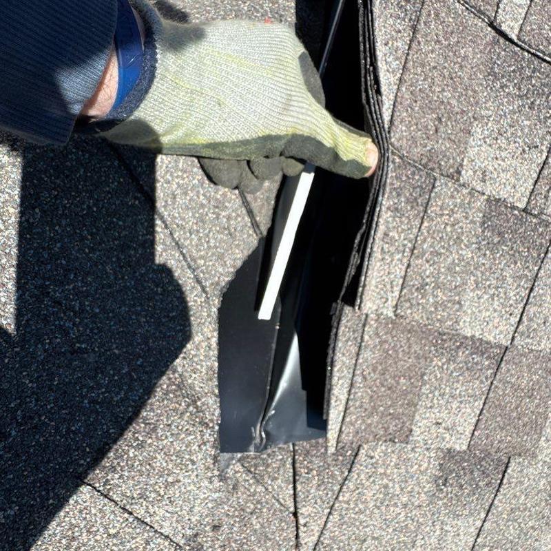 Roof flashing inspection showing lifted shingle edge