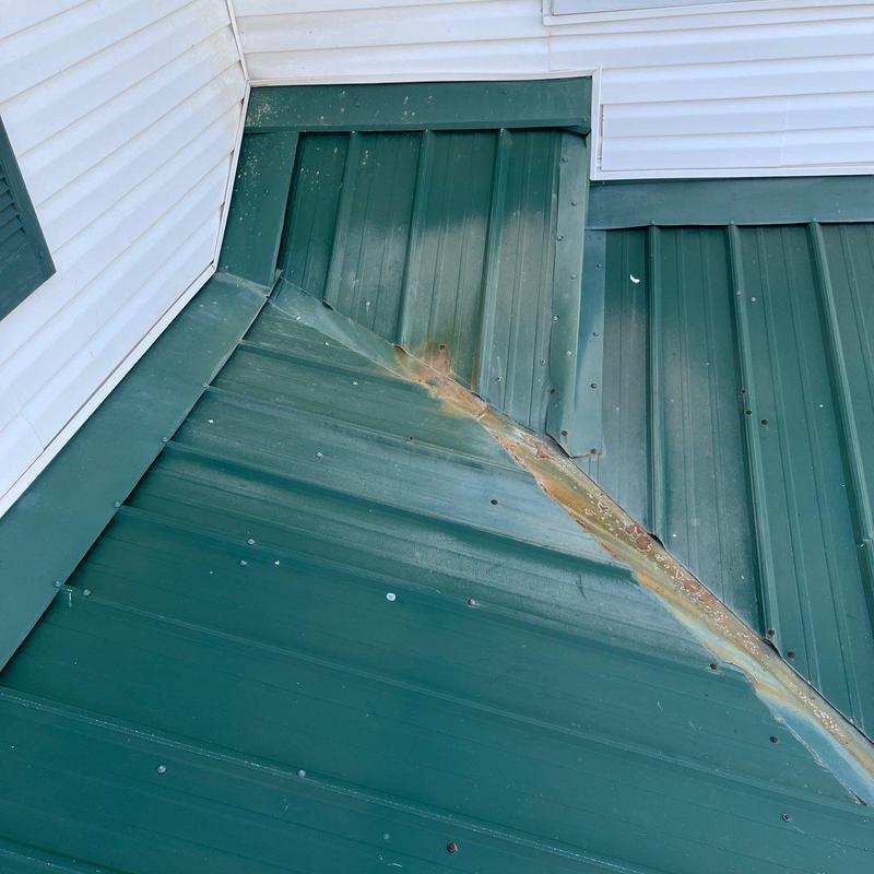 Metal roof flashing and panel junction with rust buildup
