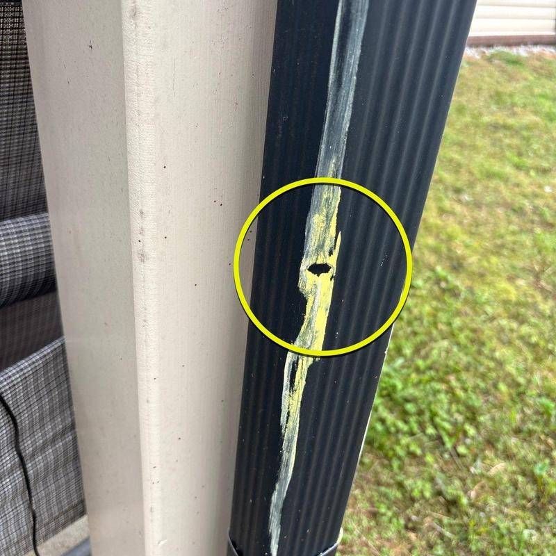 Downspout with hole and paint damage highlighted