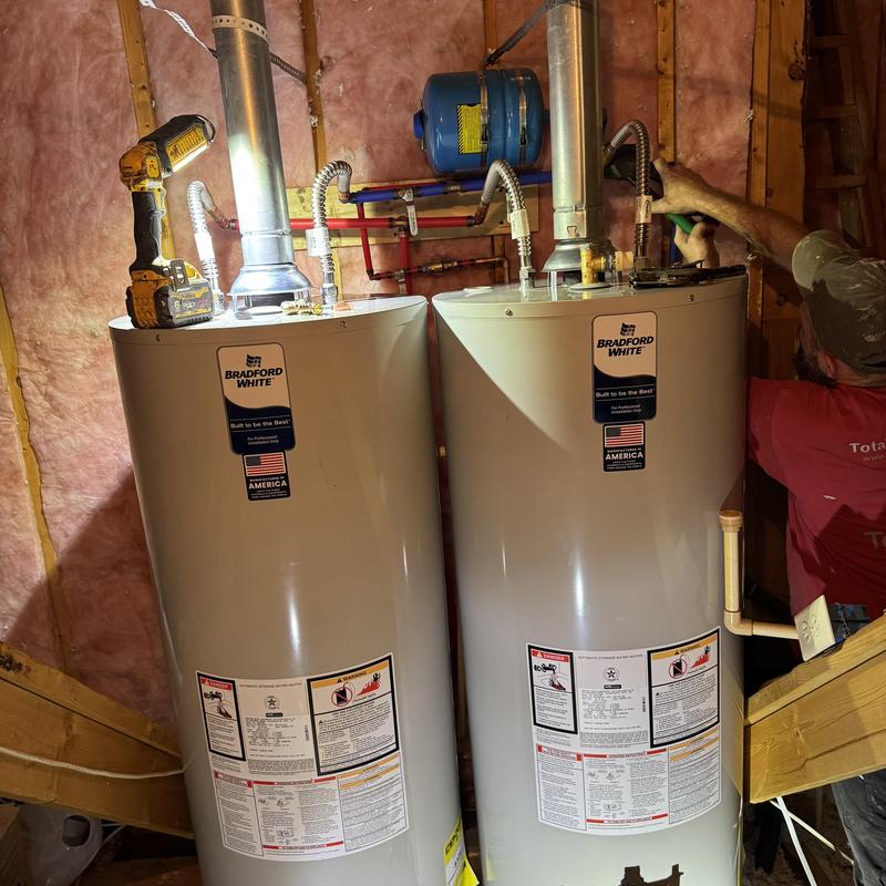 Water heaters in attic with technician working