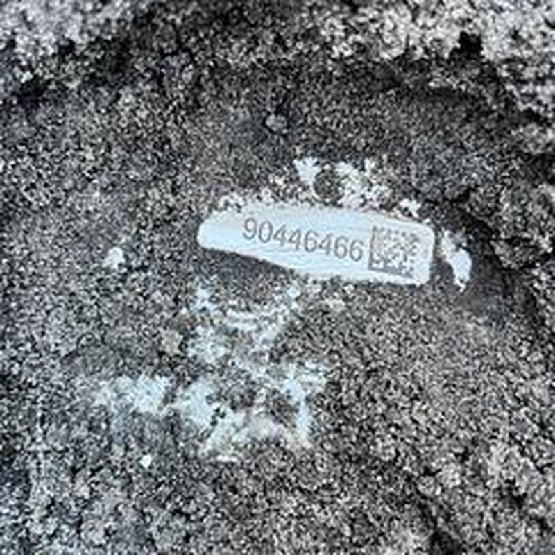 Backflow device label embedded in asphalt surface