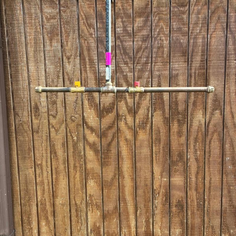 Gas line with dual shutoff valves on wood fence