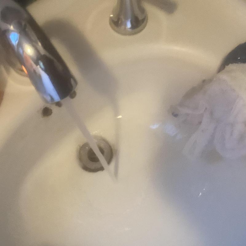 Basin sink drain with flowing water and cloth nearby