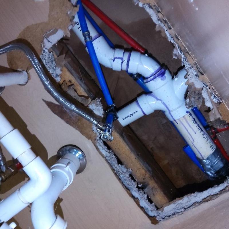PVC drain and PEX supply pipes under floor access panel