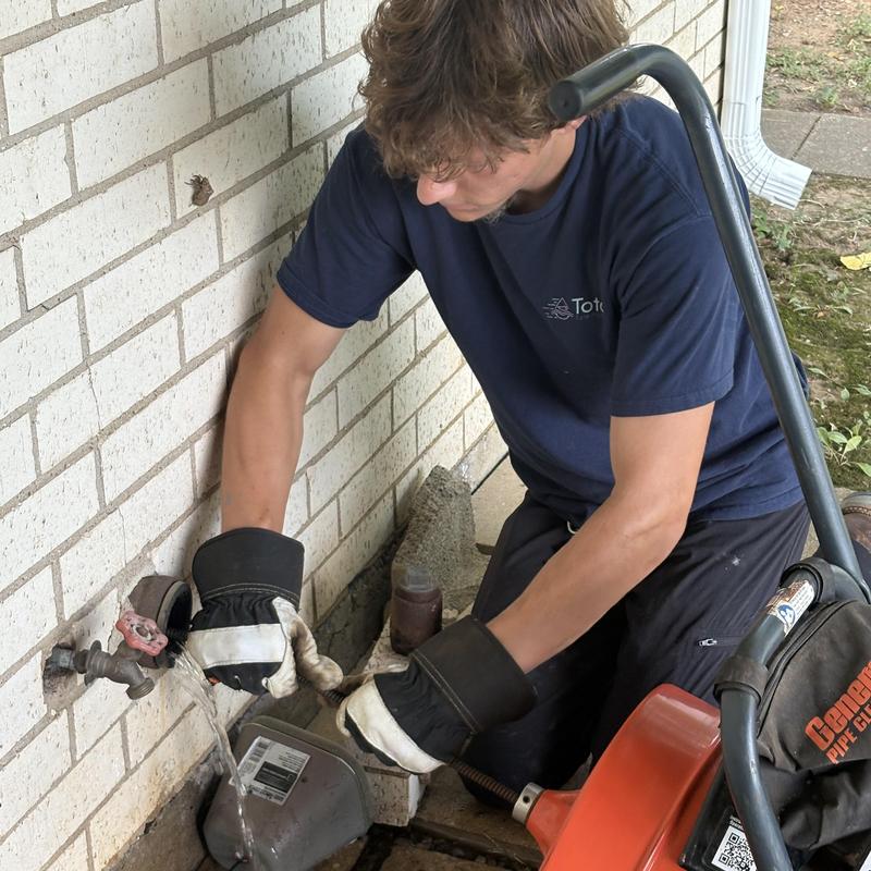 Outdoor pipe drain cleaning with plumber and drain snake