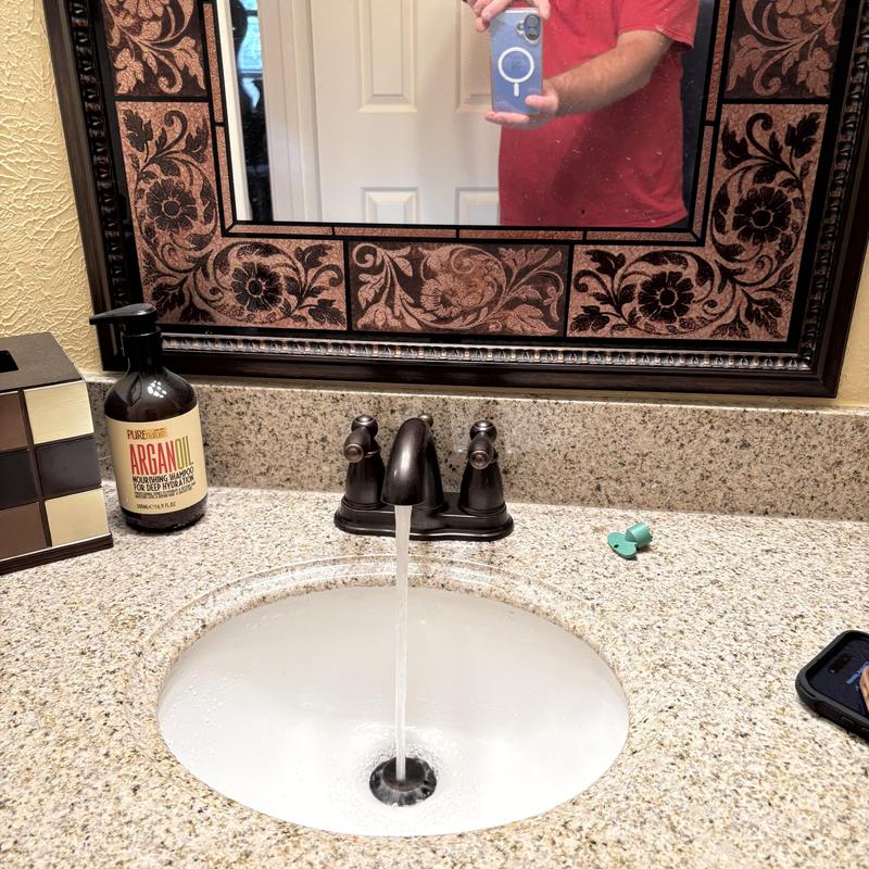 Bathroom faucet with running water on granite countertop