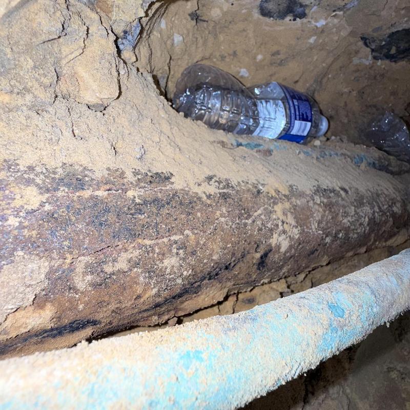 Old cast iron drain pipe in dirt tunnel access