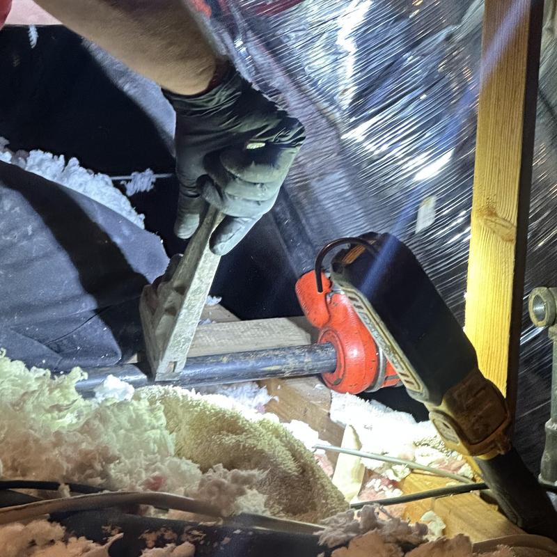 Gas line pipe installation with pipe wrench in attic