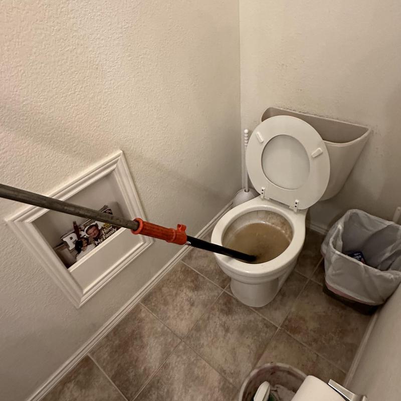 Toilet bowl unclogging with plunger tool in bathroom