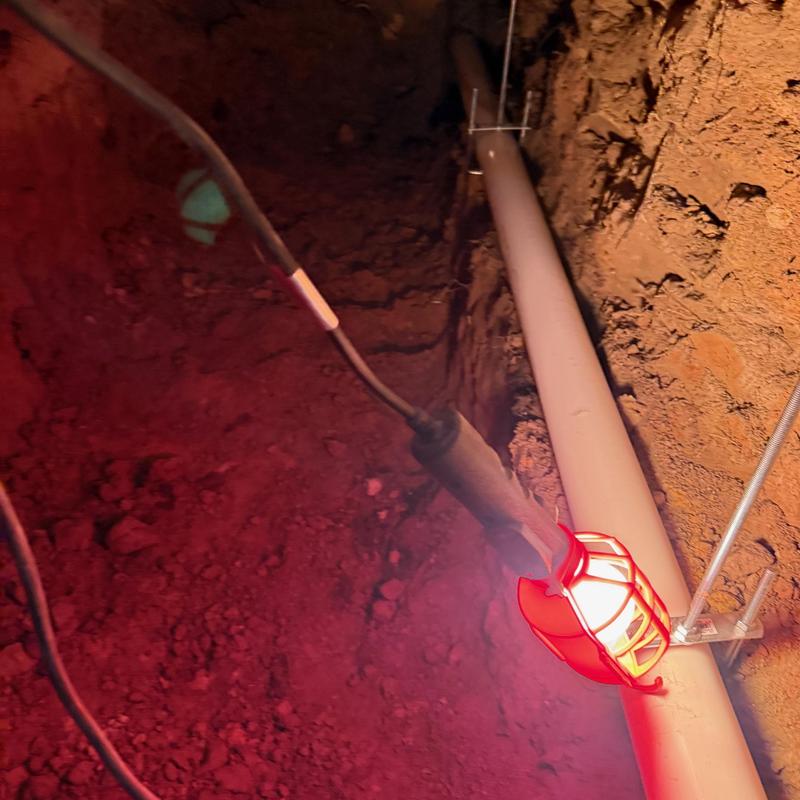 Main sewer line pipe with work light in trench