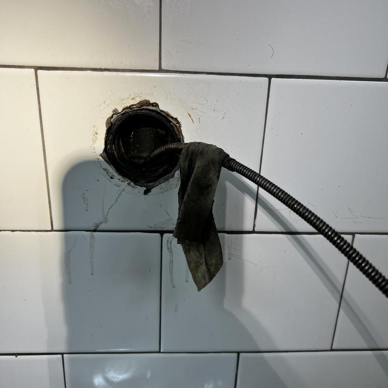 Main drain pipe cleaning with plumbing snake in wall