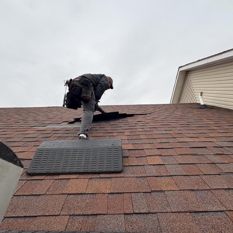 Roof shingles inspection with worker lifting shingles